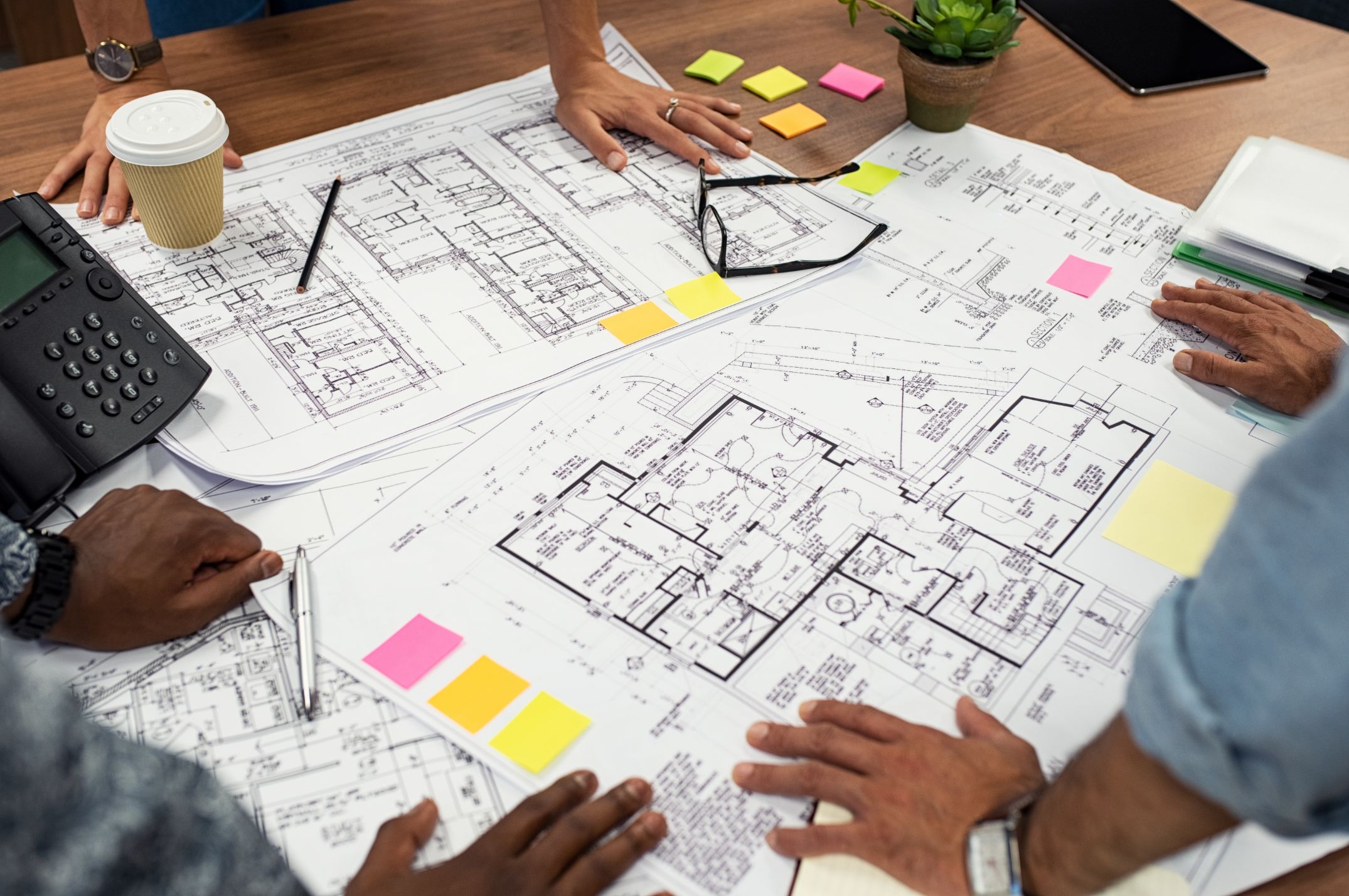 Multiple architects looking over blueprints on a table
