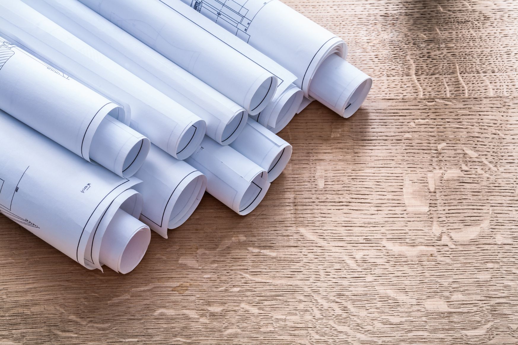 Architectural blueprints rolled up, sitting on a table