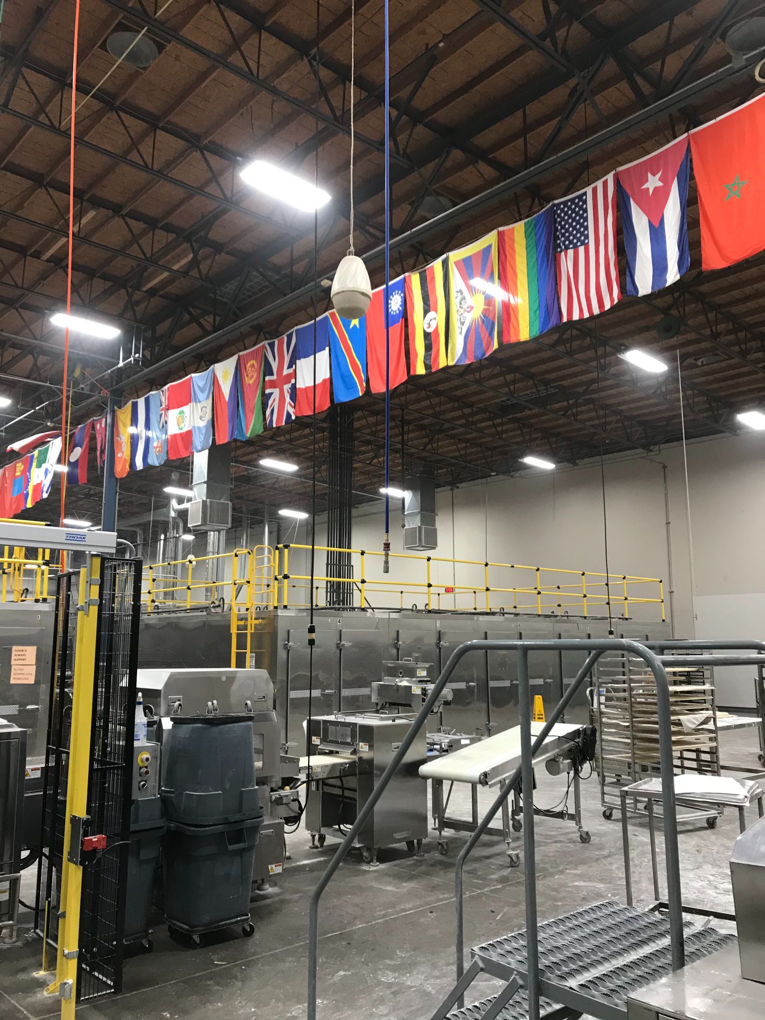 View from inside of SemiFreddis bakery, with machinery and flags hanging from the roof. 