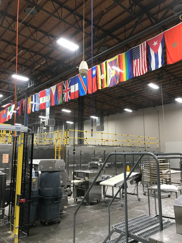 View from inside of SemiFreddis bakery, with machinery and flags hanging from the roof. 